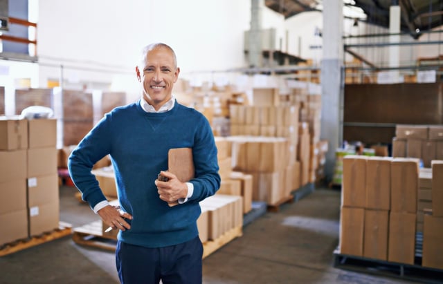 Man standing in warehouse with clipboard
